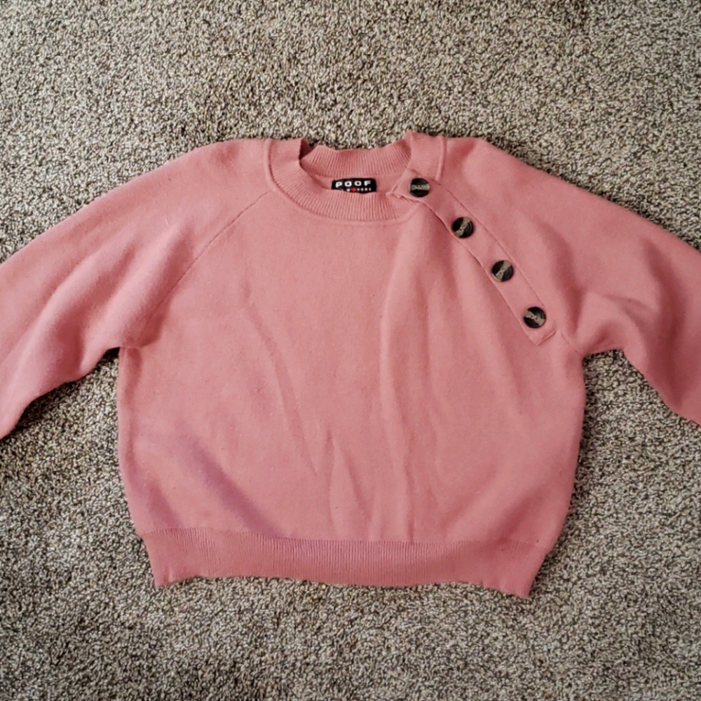 A cropped light pink sweater with cuffed sleeves.
